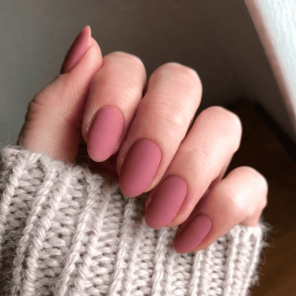 Almond nails in a matte dusty-rose mauve-pink crème; real photography.