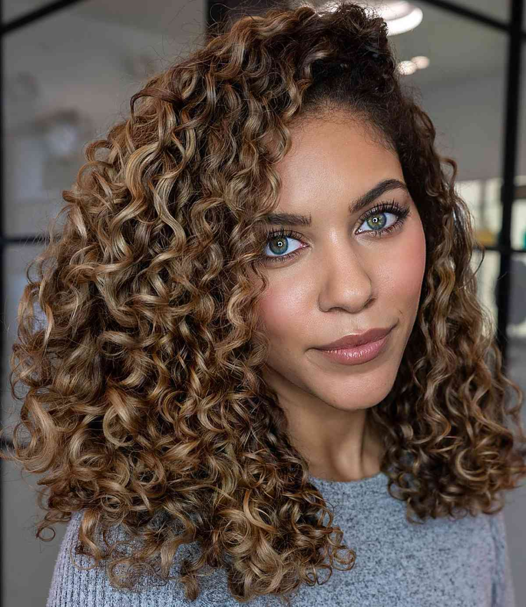 Coily curly hair in ash brown with warm highlights