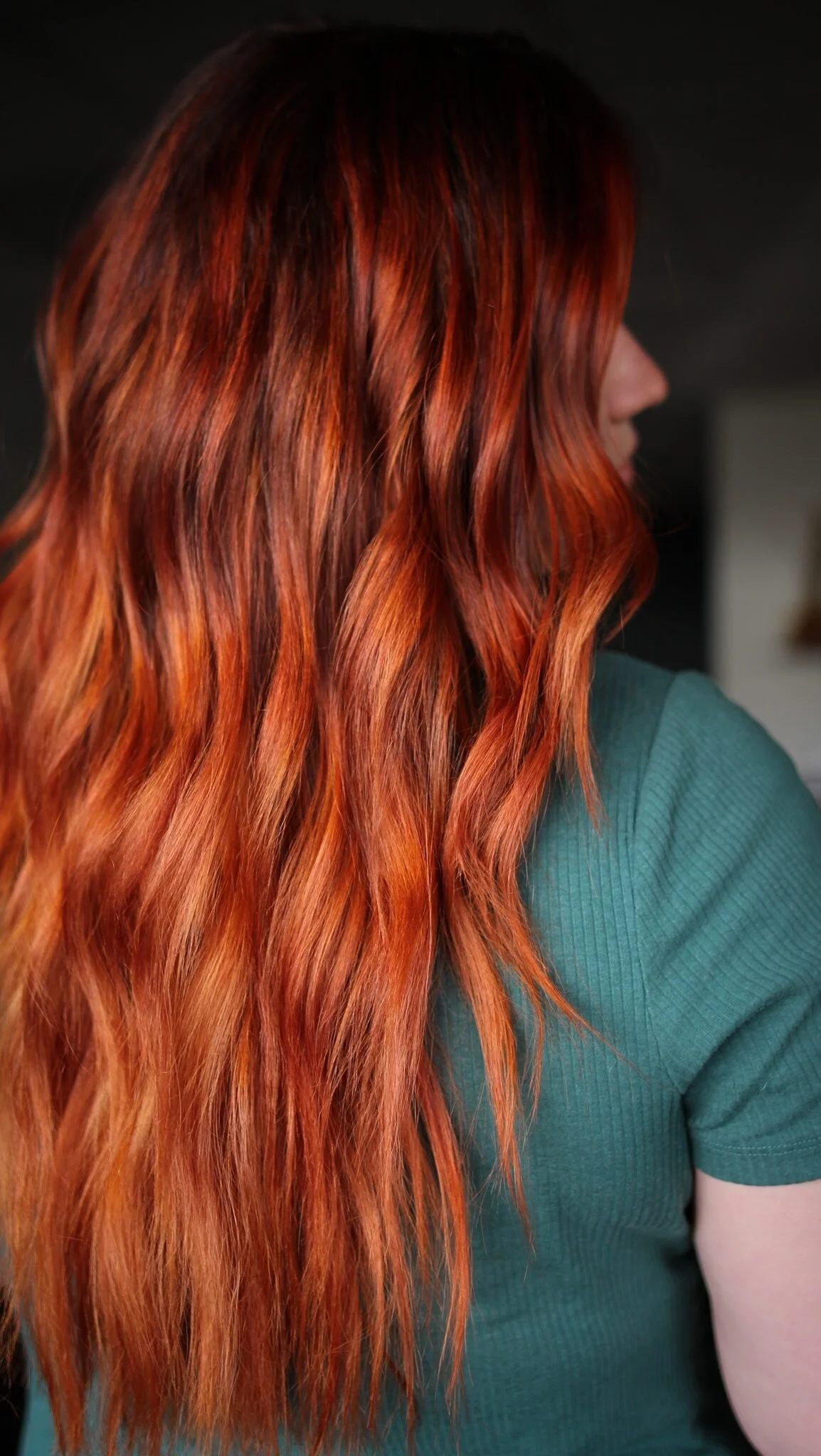 Long copper-red wavy hair with a darker shadow root