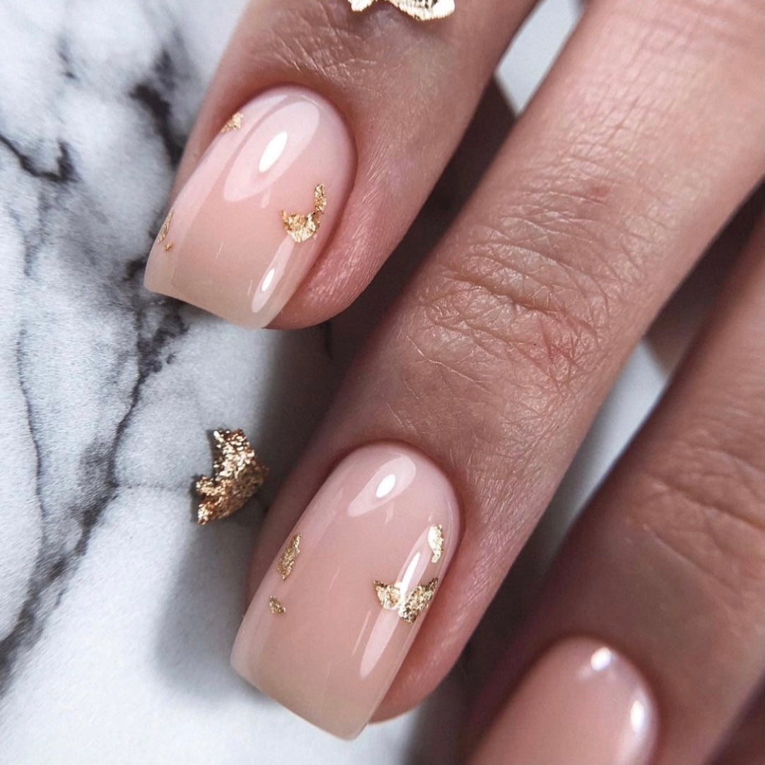 Nude nails accented with gold foil flakes