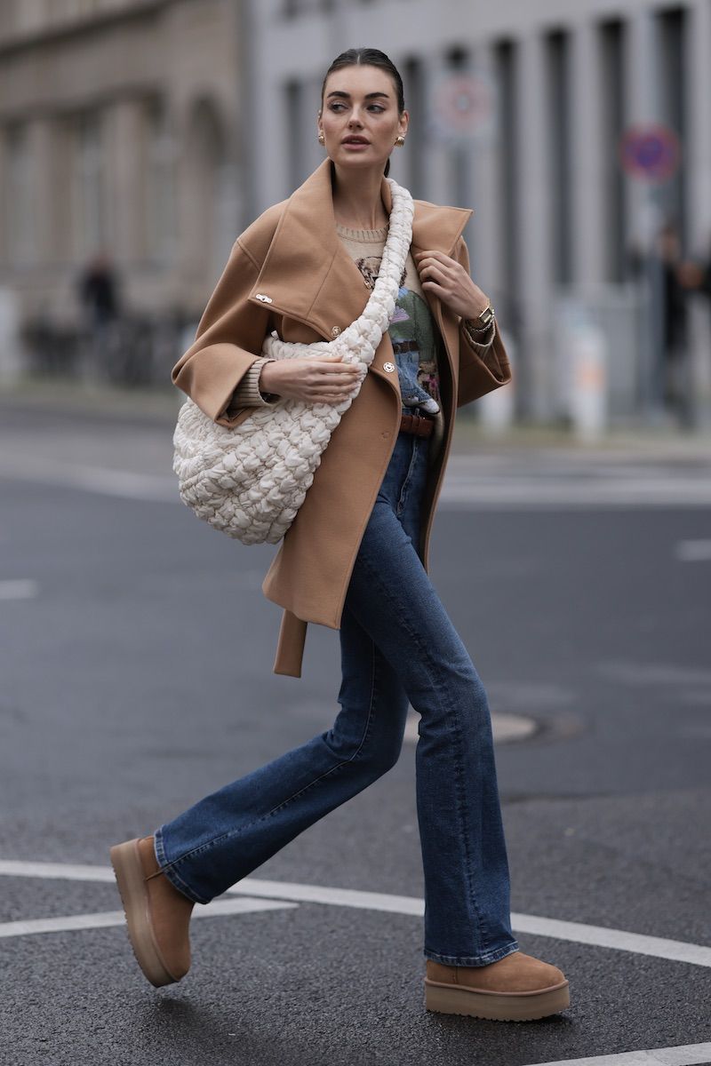 Woman in a camel coat and flared jeans wearing chestnut platform ugg boots