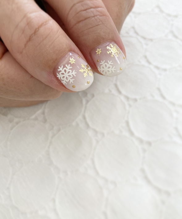 Very short sheer white Christmas nails with gold and silver snowflake stickers