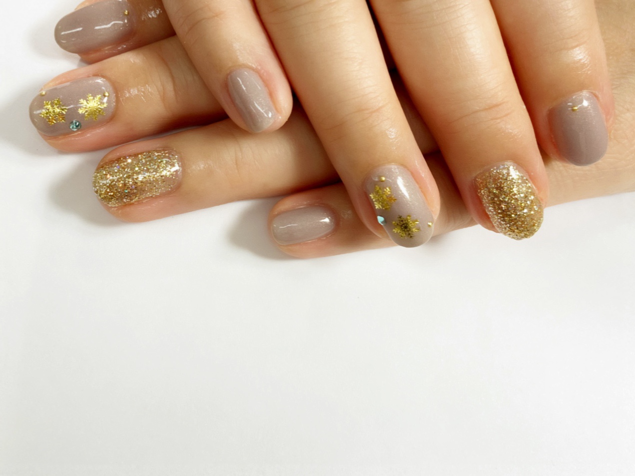 Greige nails with gold snowflake decals and gold glitter accent nails