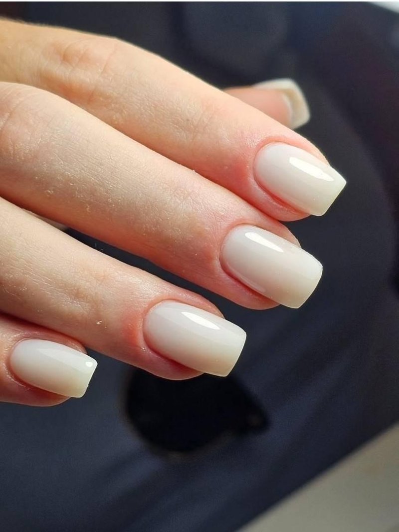 Short square nails painted in an opaque milky white polish