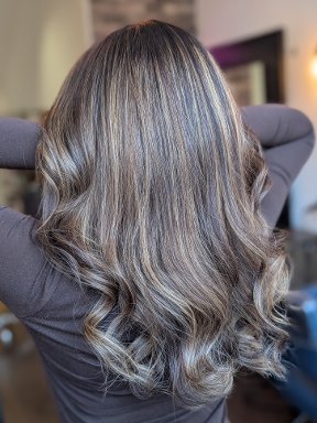 Back view of wavy hair with mushroom ash blonde balayage over a dark base