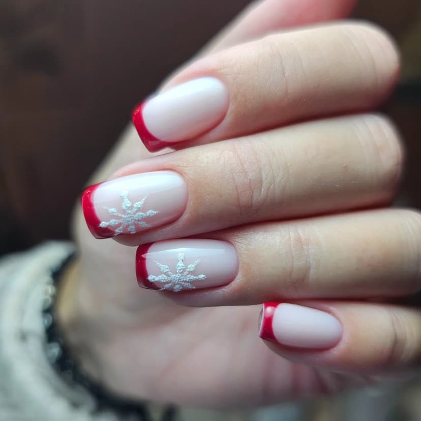 Short red French tip Christmas nails with white snowflake art on a milky white base