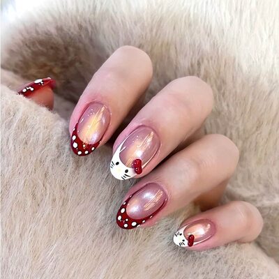 Medium almond nails in sheer chrome nude with red French tips, white polka dots and a Hello Kitty face with a red bow