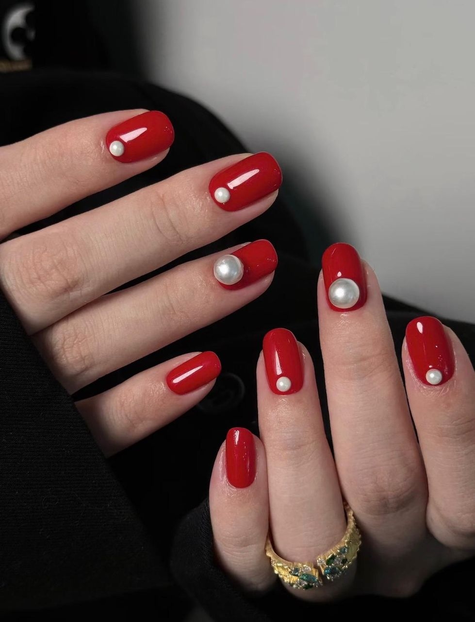 Cherry red nails decorated with small pearl accents