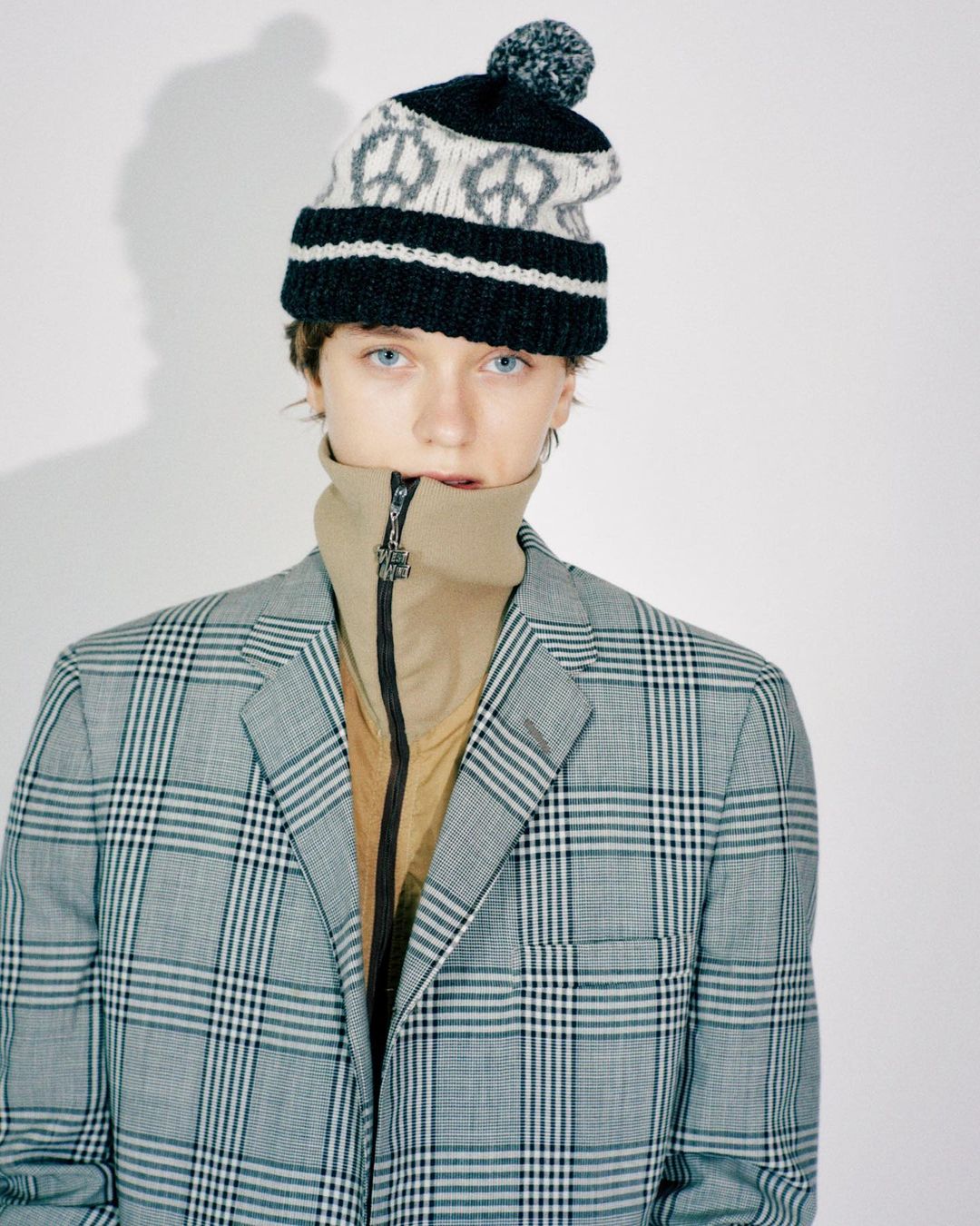 Editorial photo of a fair-isle pom beanie with a plaid blazer
