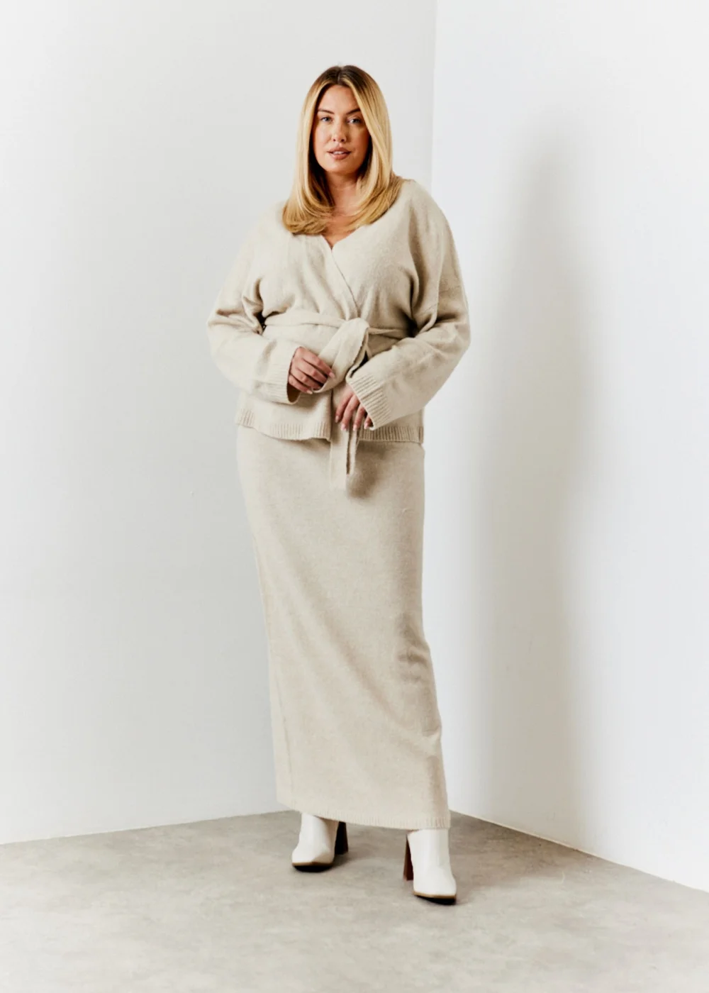 Woman wearing an oatmeal knit co-ord with a wrap top and maxi skirt, styled with white ankle boots