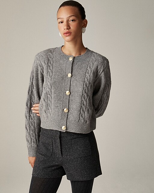 Woman wearing a grey cable-knit buttoned cardigan with black tweed shorts and tights