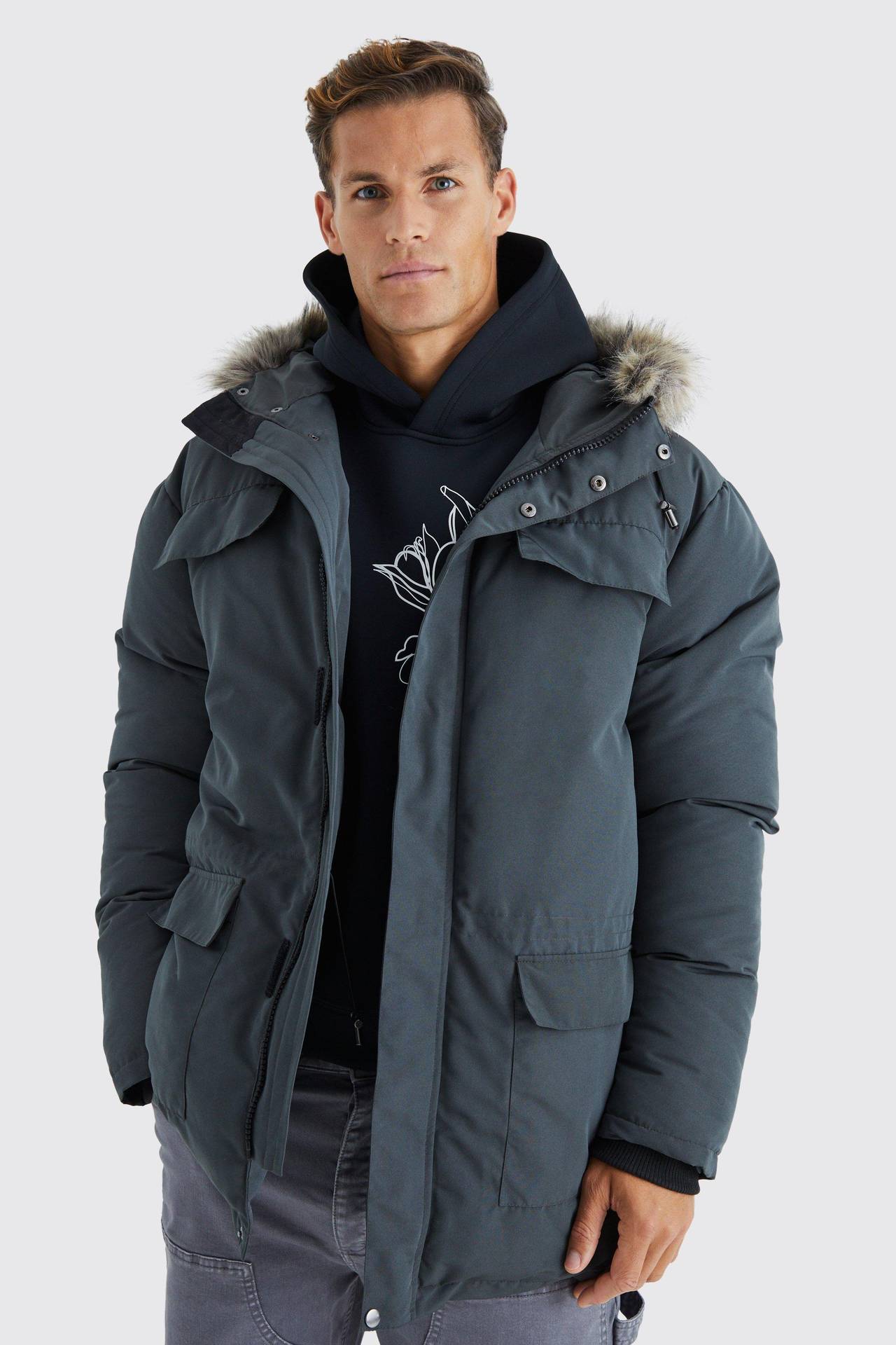 Man wearing a charcoal hooded parka with fur trim over a black hoodie