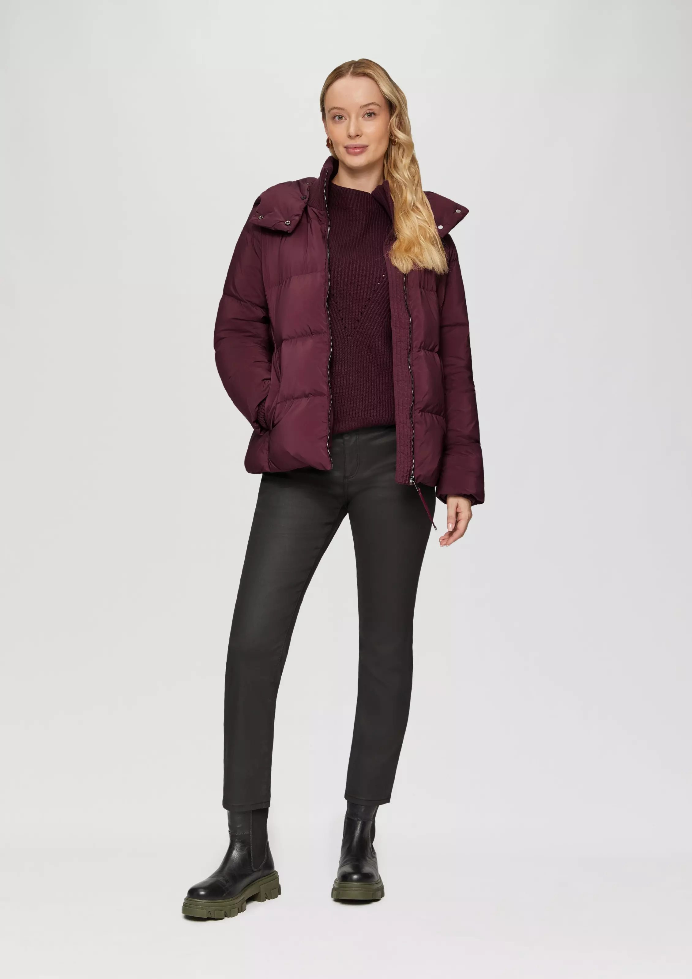 A wine-colored puffer jacket with a matching knit, black coated jeans and chunky Chelsea boots