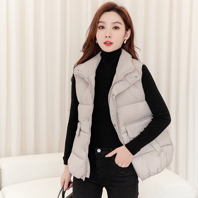 Woman in a light gray puffer vest over a black turtleneck and black jeans