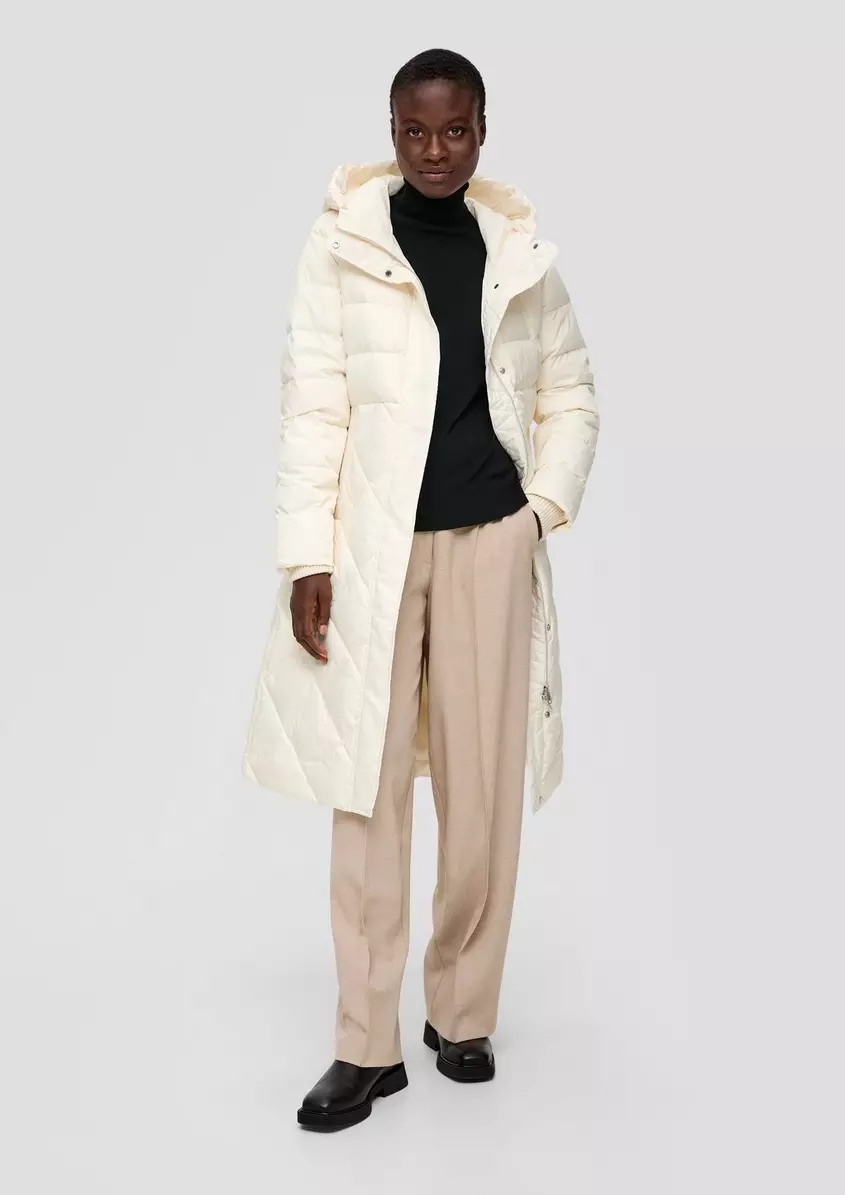 A woman wearing a cream long puffer coat with a turtleneck and tailored pants