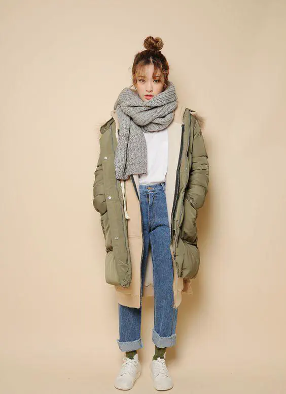 Olive parka with fur hood lining, chunky gray scarf, white tee, blue jeans and white sneakers