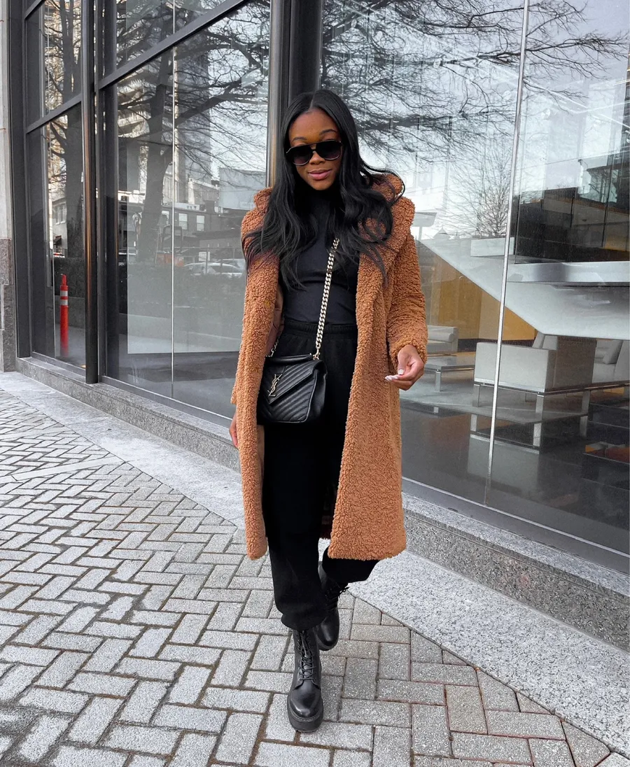 Woman in a caramel teddy coat with black combat boots and a quilted bag
