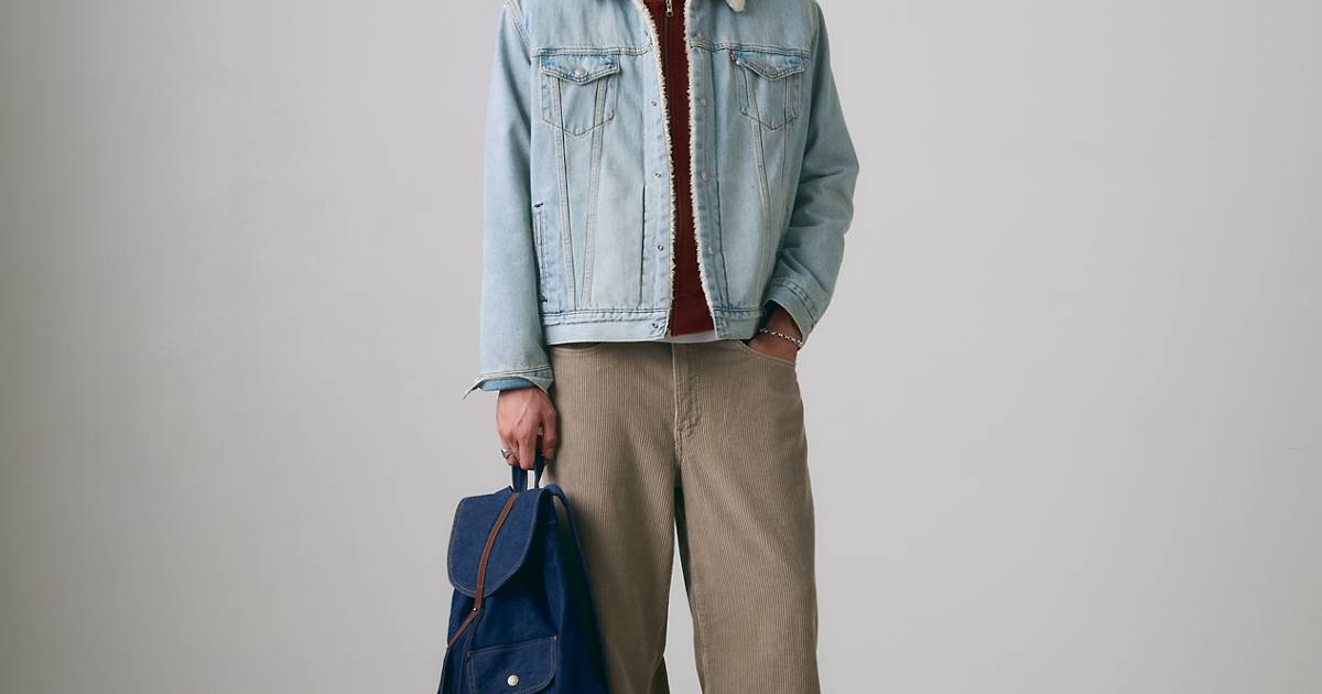 Model wearing a sherpa-lined denim trucker jacket with tan corduroy pants