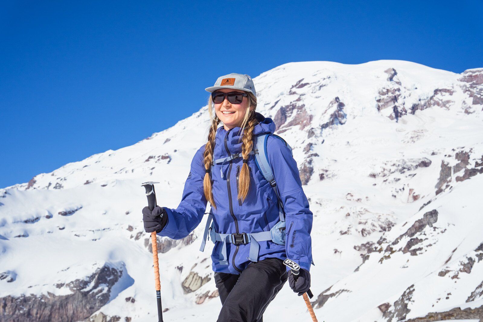 Woman in a ski-touring shell jacket climbing a snowy slope
