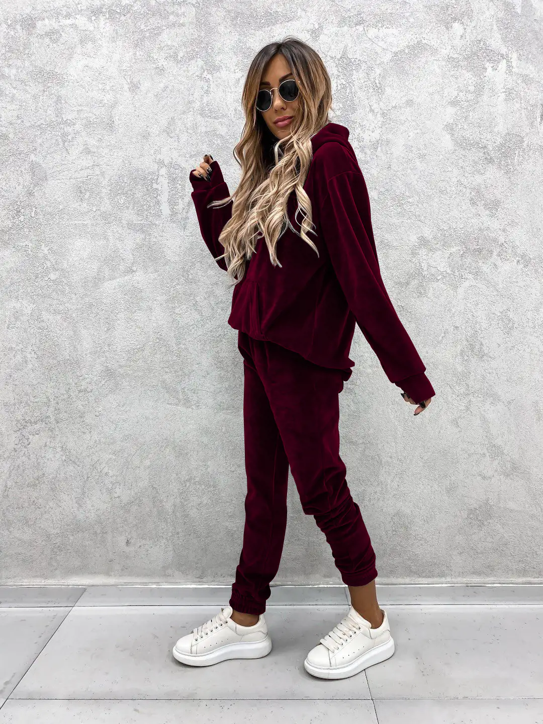Woman in burgundy velour tracksuit and white platform sneakers