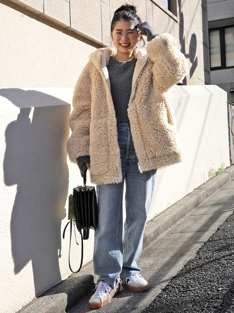 Woman in a cream teddy fleece jacket with medium-wash wide-leg jeans, white sneakers and a black tote