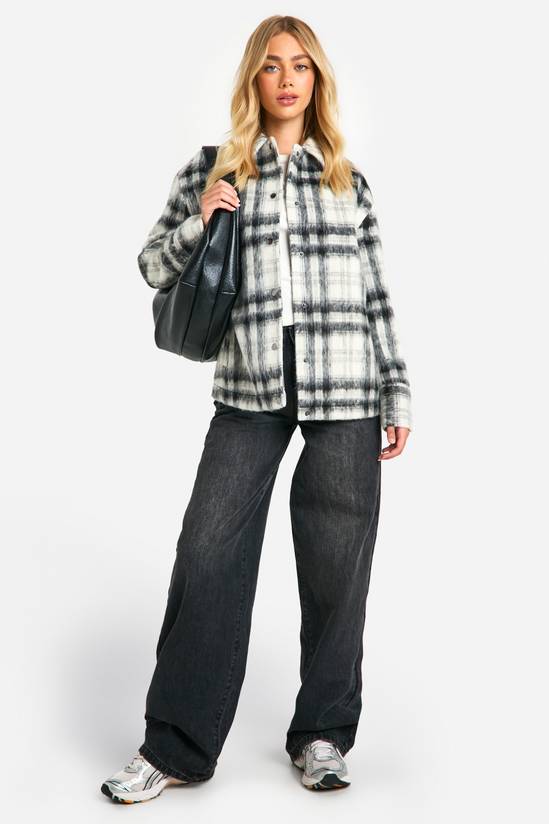 Woman in a black-and-white plaid shacket with black wide-leg jeans, silver sneakers and a black bag