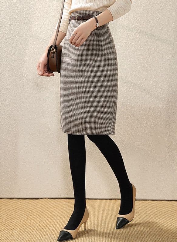 Woman wearing a houndstooth check midi pencil skirt with a cream knit sweater and black tights
