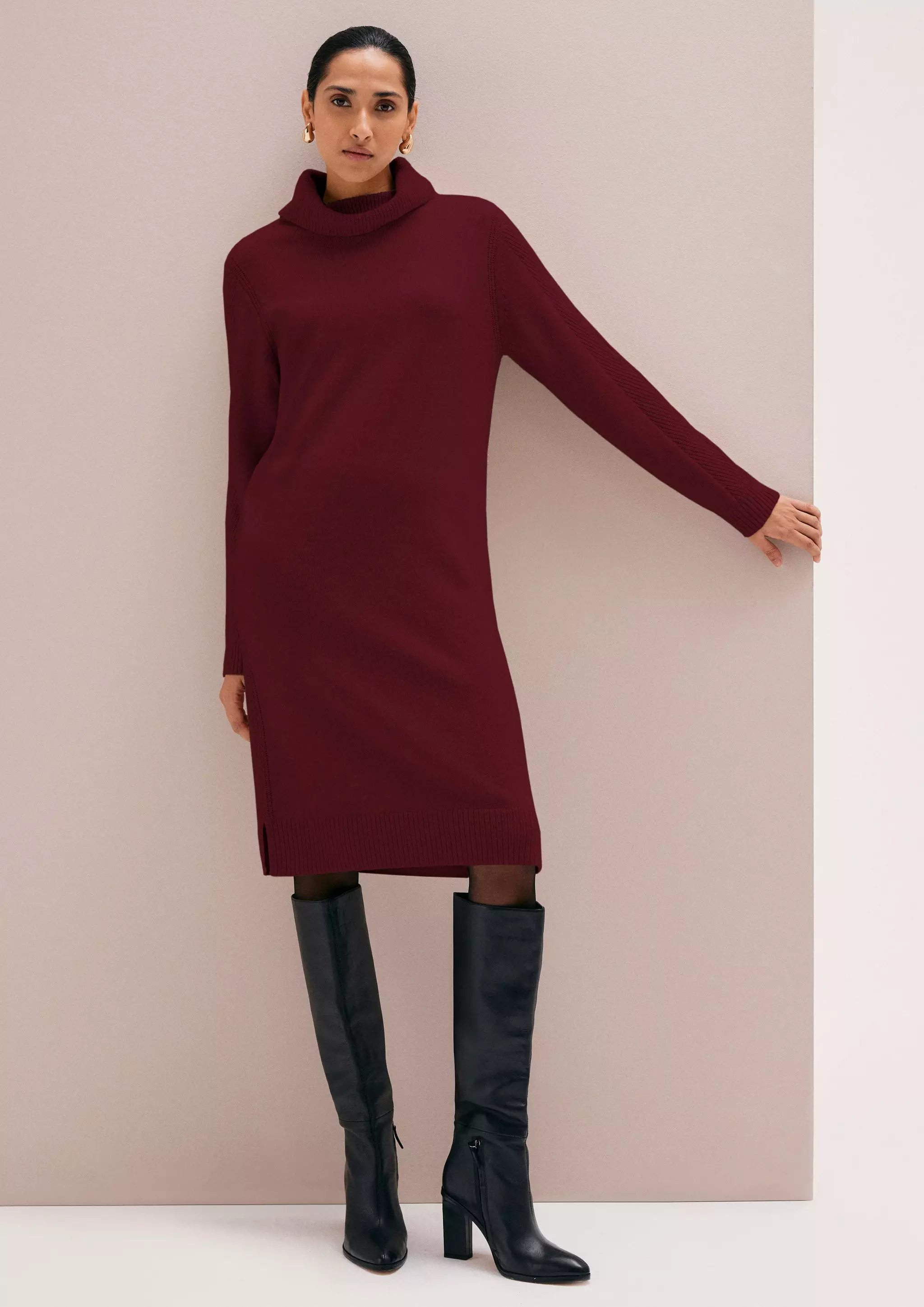 Woman wearing a burgundy turtleneck sweater dress with black knee-high boots