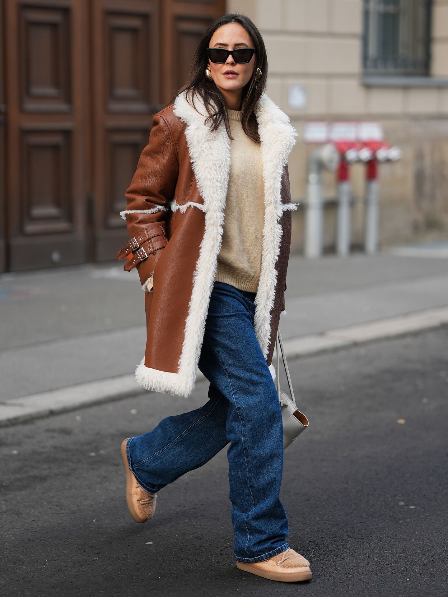 Woman in a shearling coat, jeans and a cozy sweater with ankle boots