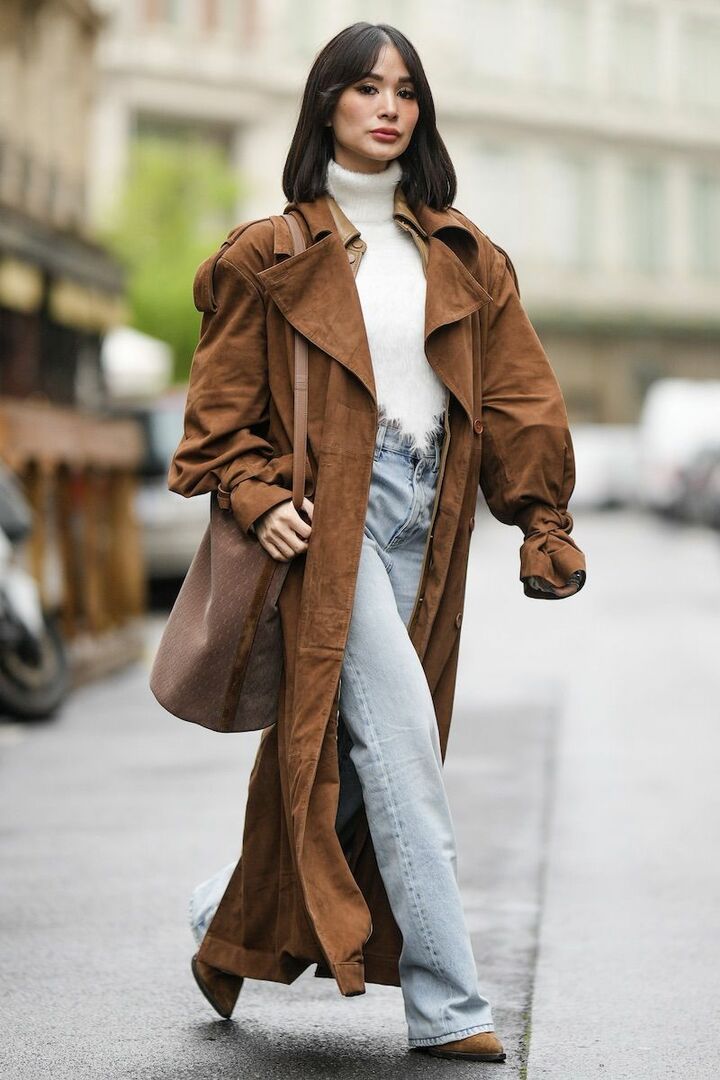 Woman wearing cognac suede pointed ankle boots with a brown suede trench coat, white turtleneck and light-wash jeans