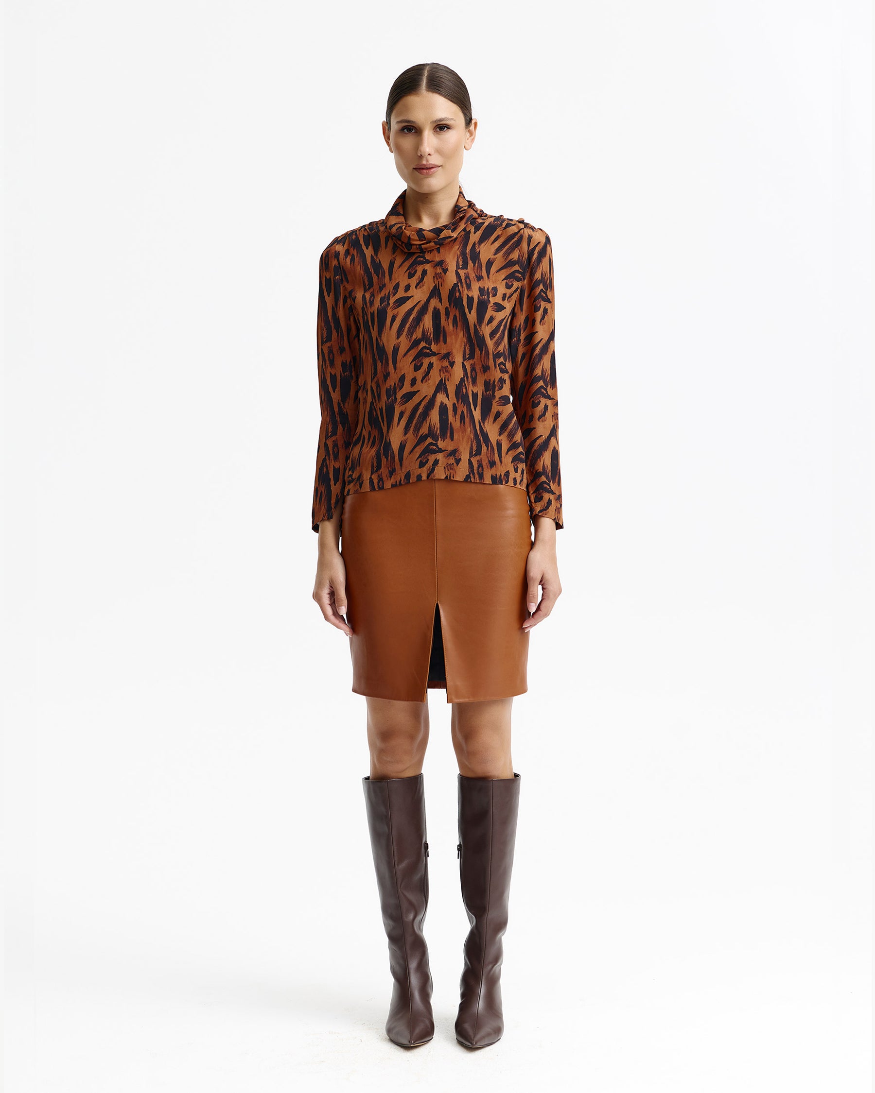 Woman wearing an animal-print cowl-neck blouse, cognac leather pencil skirt and dark brown knee boots