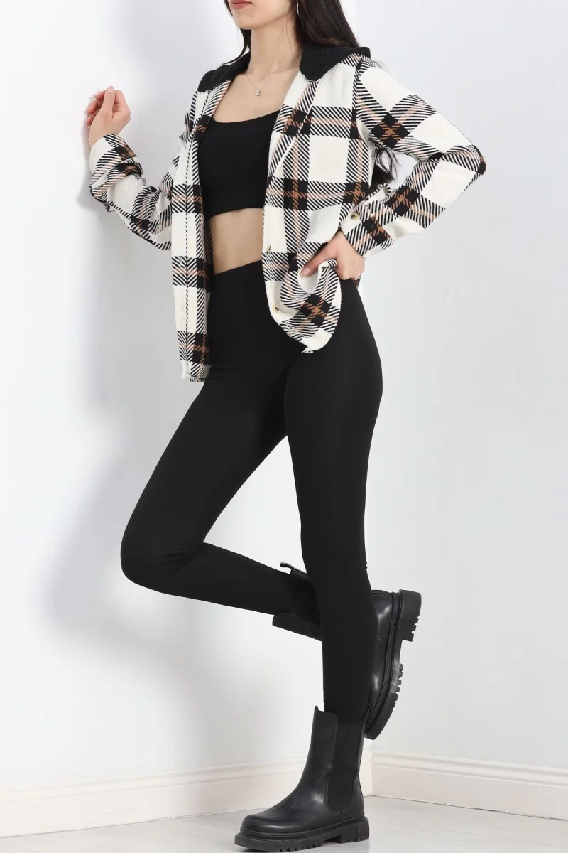 Woman in a cream plaid shacket, black top and leggings with black lug Chelsea boots