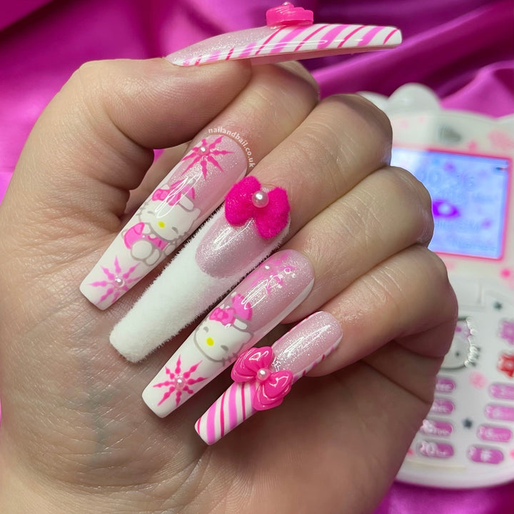 Long coffin nails in hot pink and white with Hello Kitty faces, 3D pink bows with pearls, candy cane stripes and a fuzzy white nail