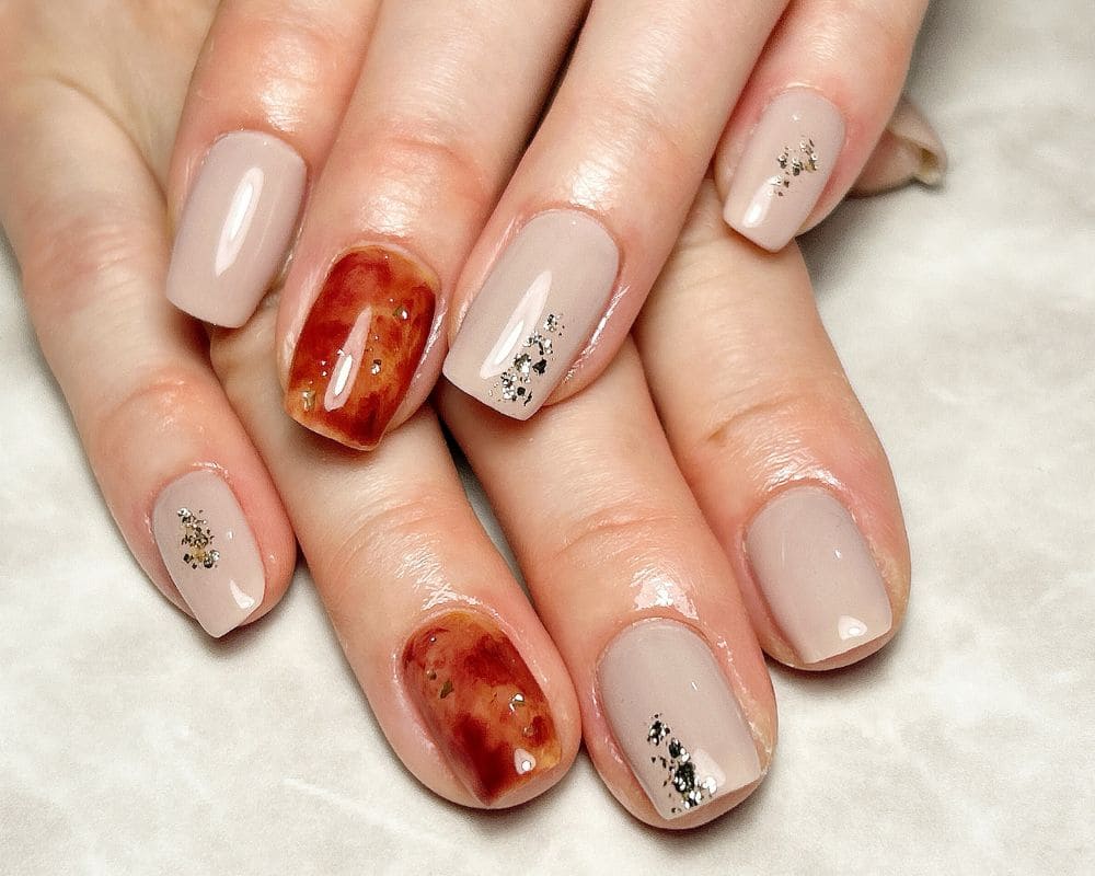 Short nails in warm beige with tortoiseshell accent nails