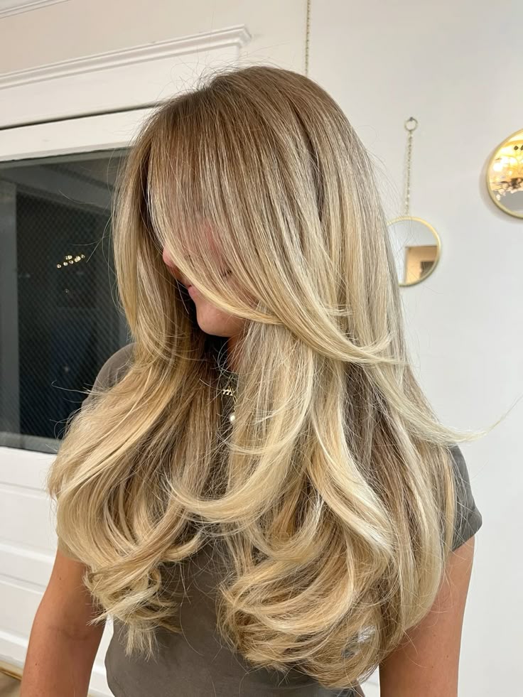 Long blonde layered haircut with face-framing layers and soft waves