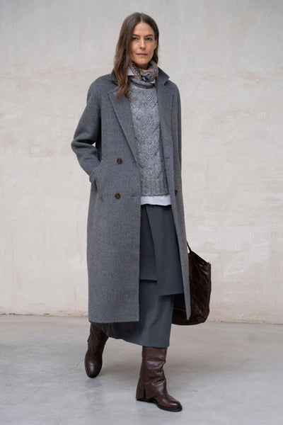 Woman in an all-grey winter outfit with a tailored coat and knit layers