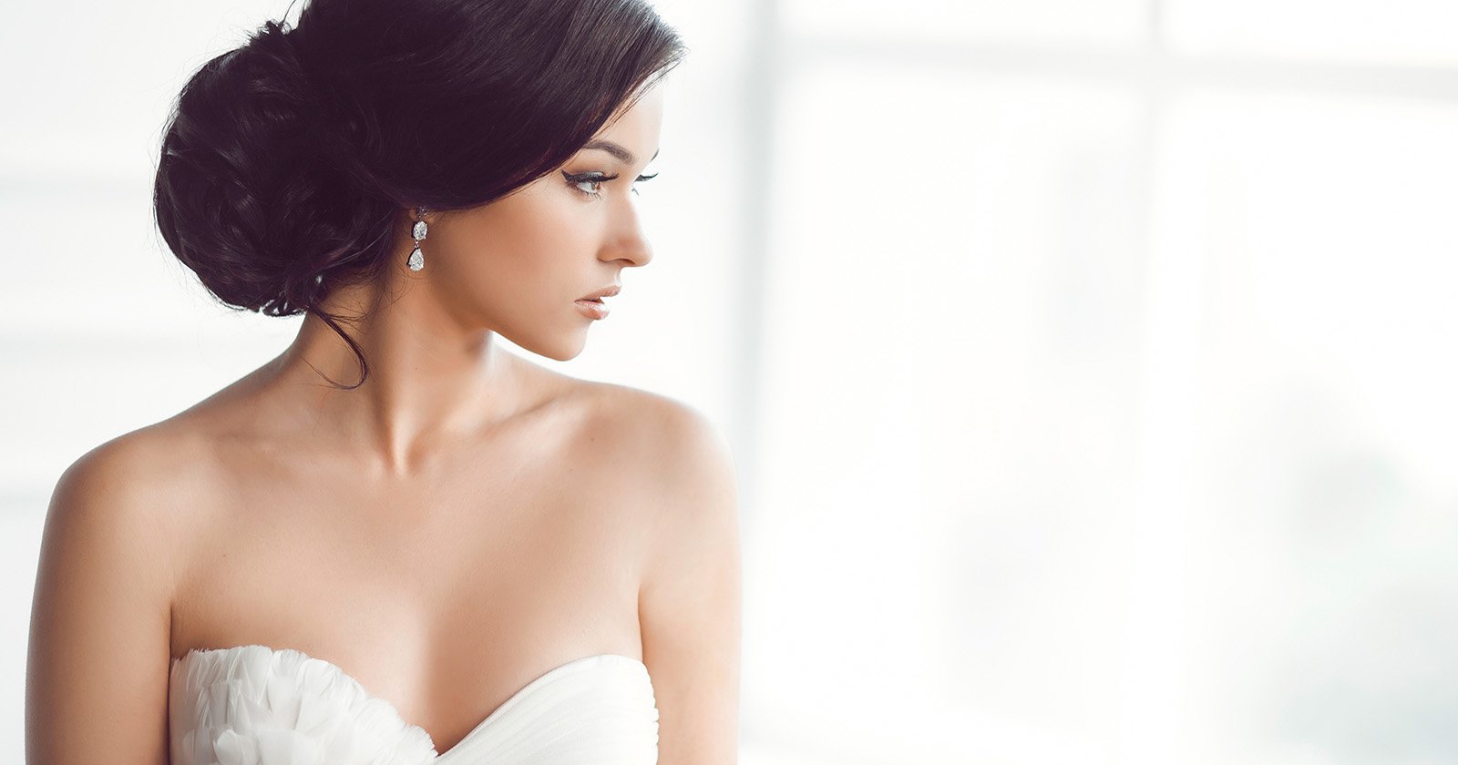 Bride with dark hair in a sleek middle-part low bun wearing a strapless gown