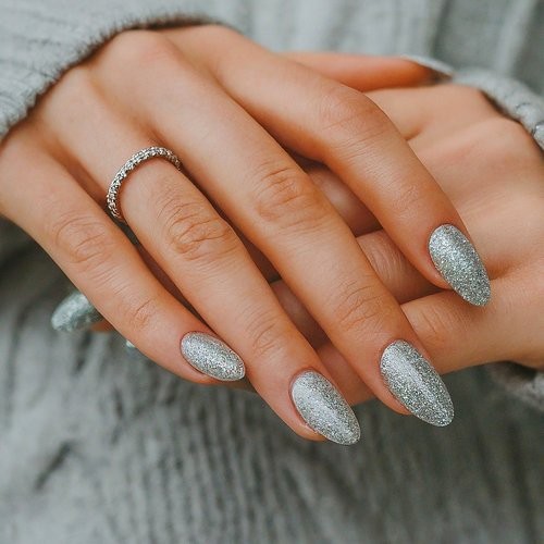 Short almond nails fully covered in fine silver glitter polish