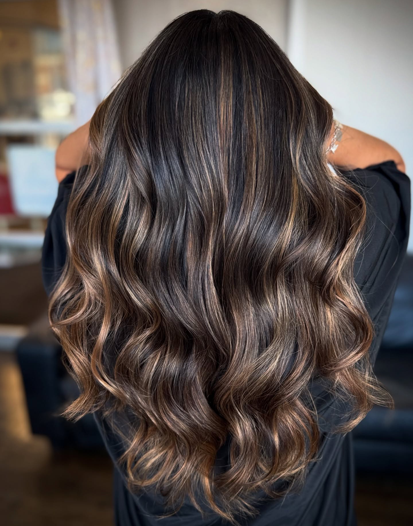 Back view of long glossy wavy hair with dark roots and caramel copper balayage highlights
