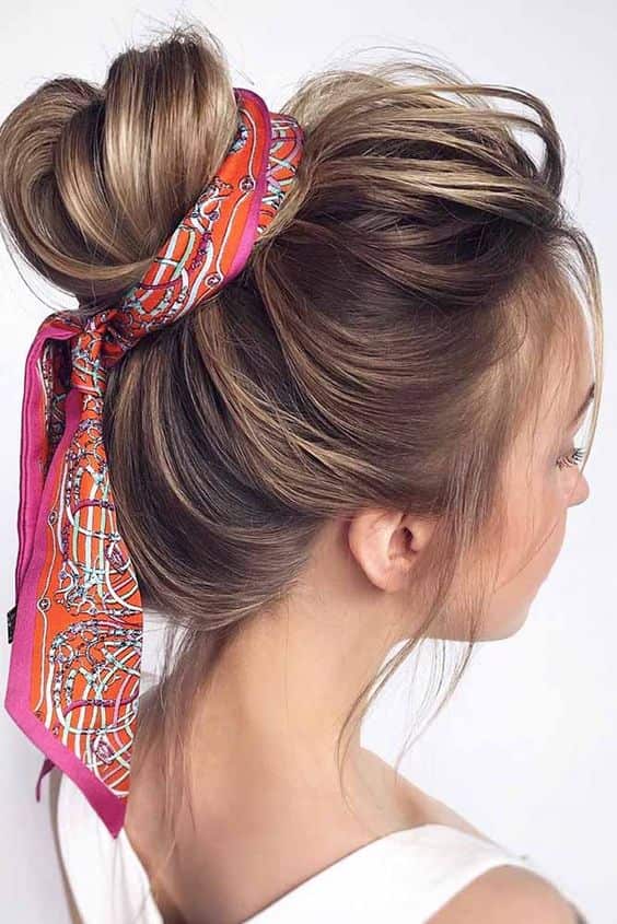 High messy bun with an orange and pink printed silk scarf tied around its base