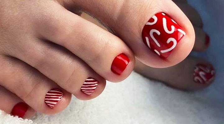 Red pedicure with white candy cane swirl art on the big toes