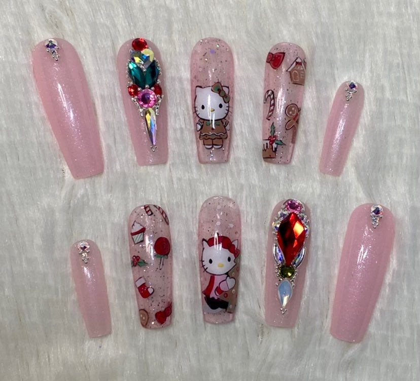 Long coffin press-on nails in sheer pink glitter with Hello Kitty faces, gingerbread men, candy canes and large red and green rhinestone clusters