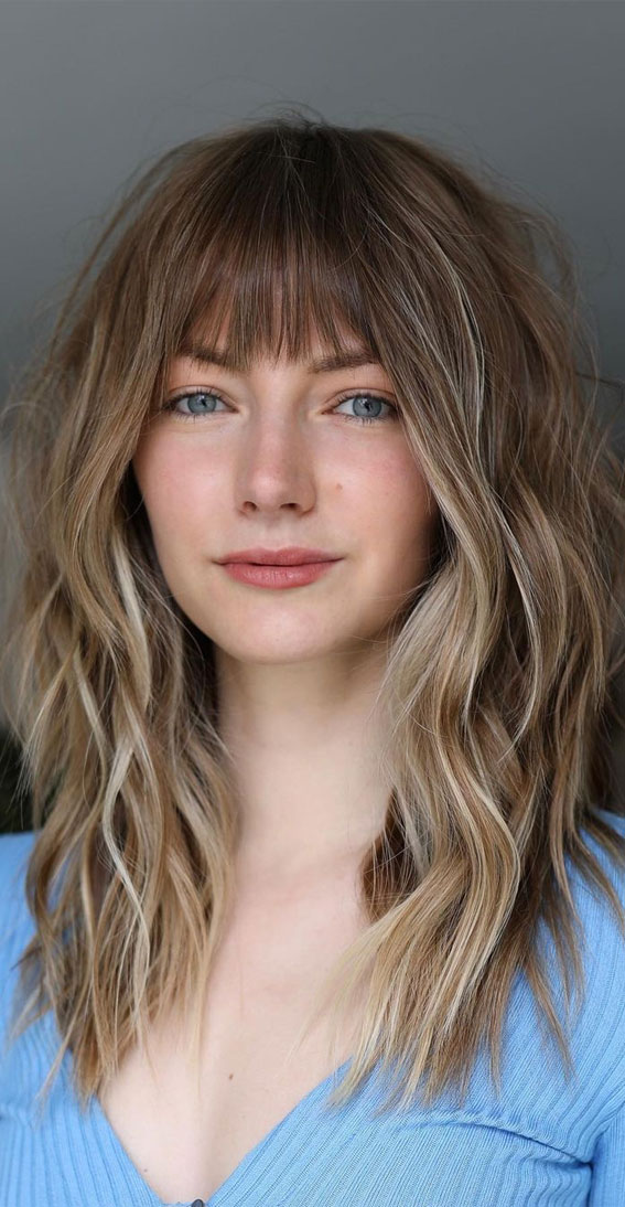 Medium-length haircut with soft wispy bangs and loose layers