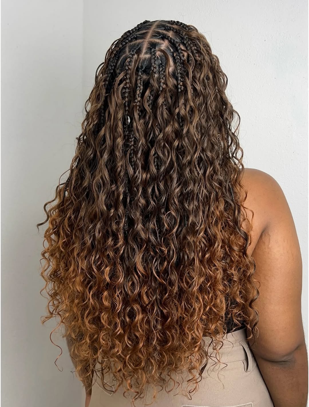 Dark-rooted boho braids melting into caramel curly ends, back view