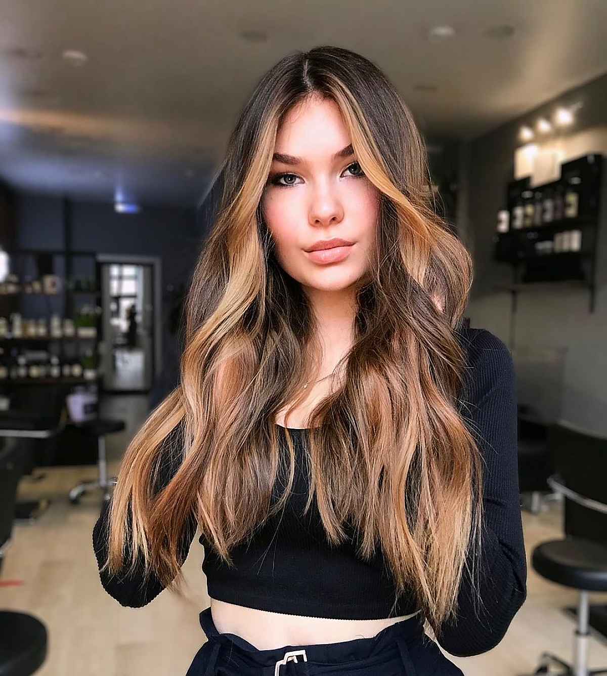 Woman with long layered hair and blonde money-piece highlights framing her face
