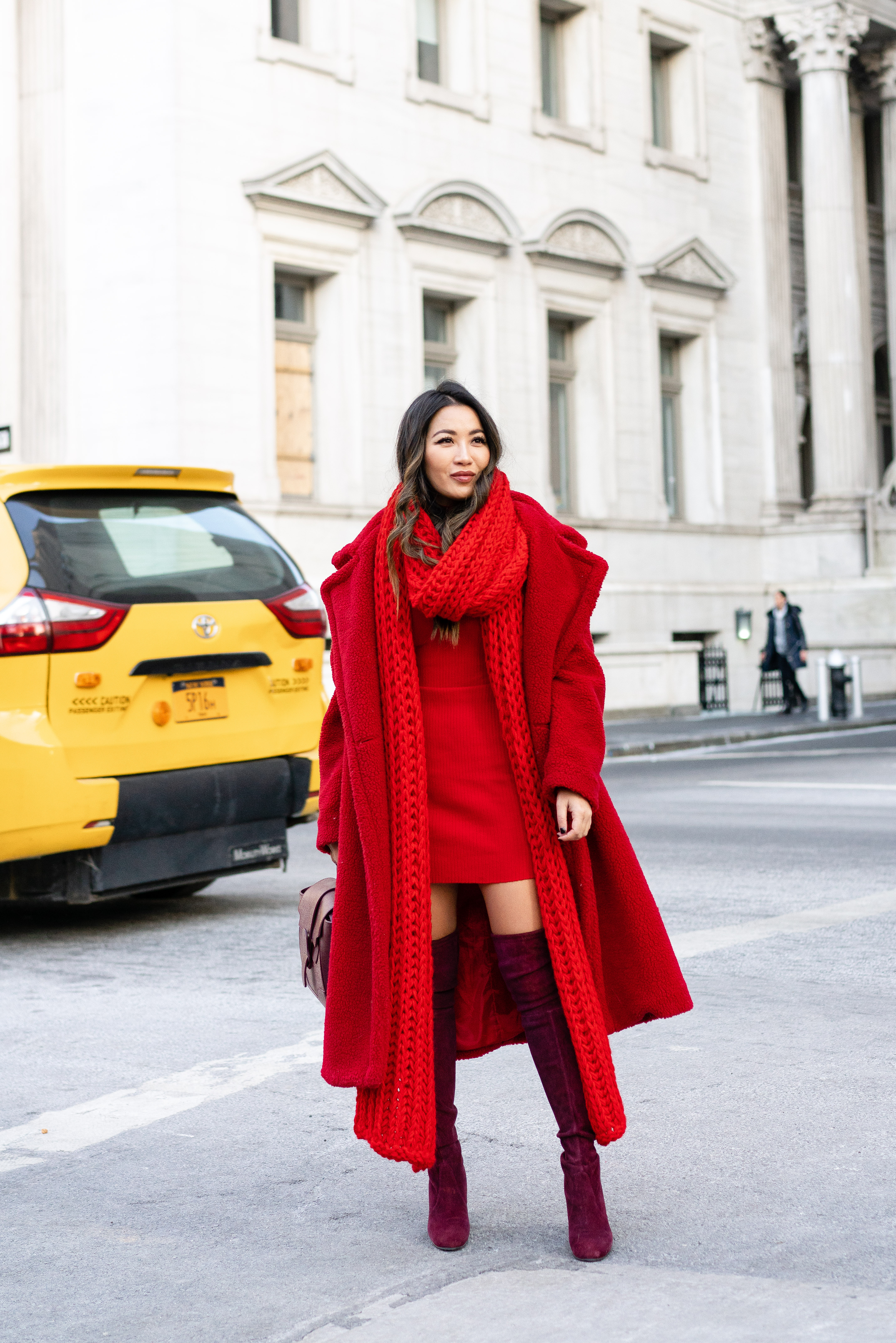 Woman wearing a burgundy red knit dress with a black coat