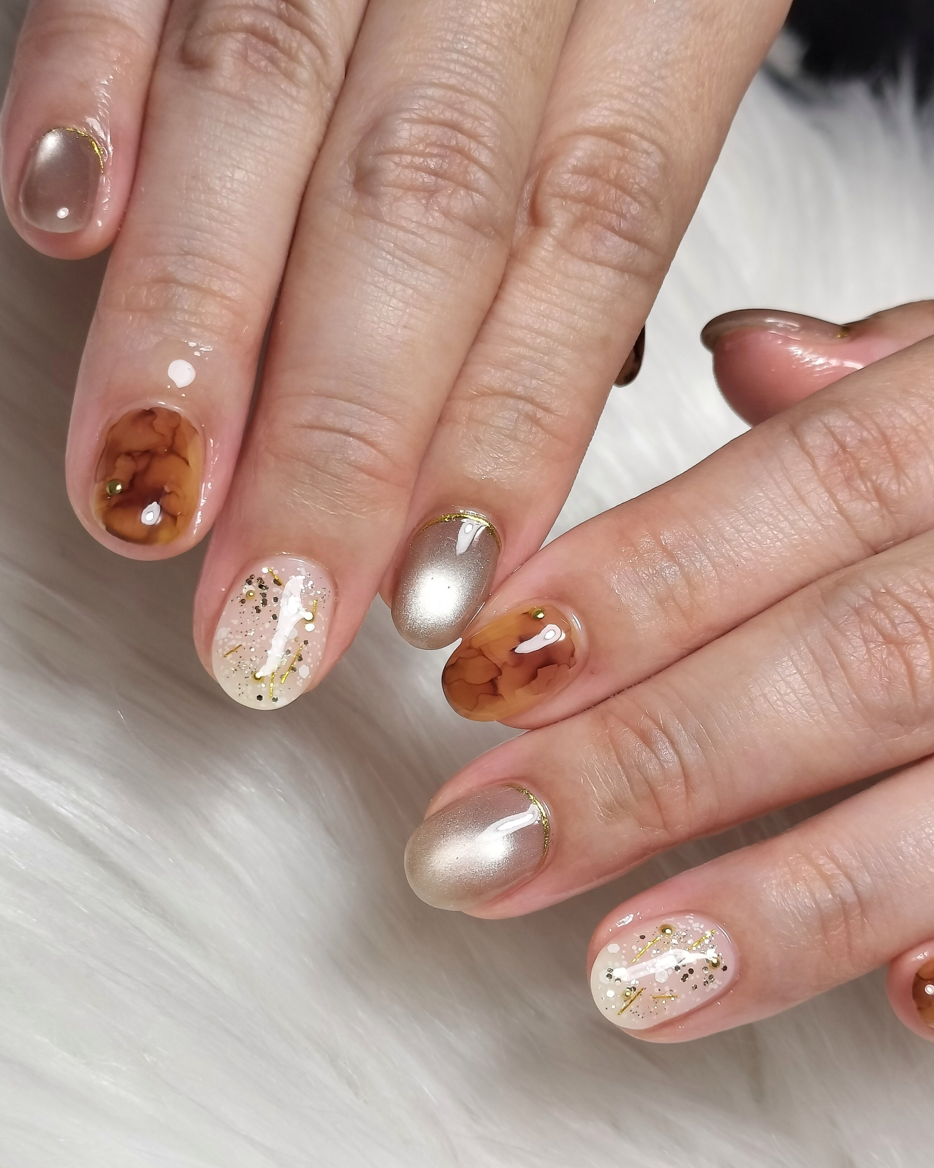 Short round nails with tortoiseshell amber accents, champagne shimmer and gold foil flakes