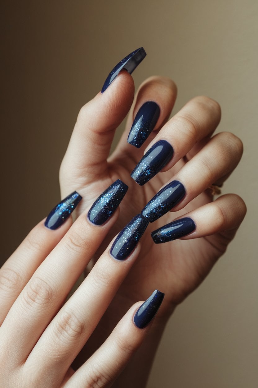 Midnight blue nails with sparkling glitter accents