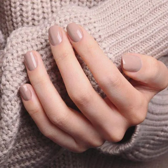 Warm taupe greige creme nail polish on short nails with a chunky knit sweater