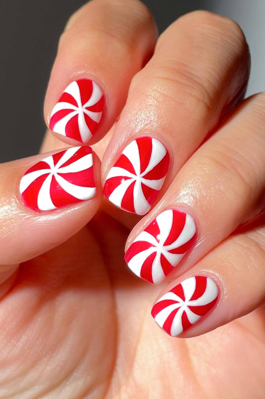Short almond nails with red-and-white pinwheel swirls like peppermint candy.